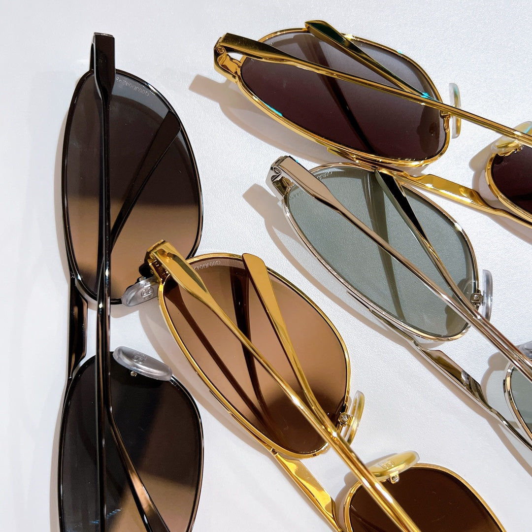 Assorted sunglasses with gold and black frames, dark lenses, and reflective finish