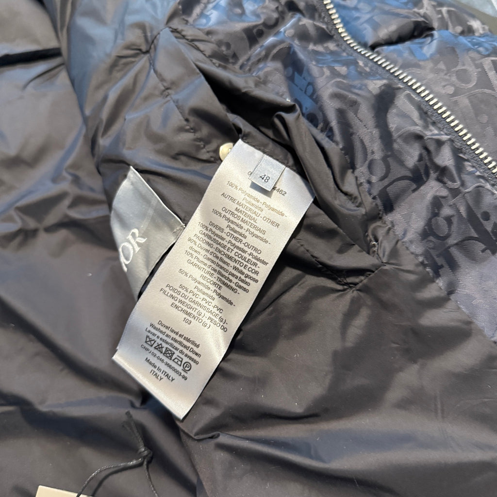 Dior size and care tags on interior lining of dark logo puffer jacket, close-up.
