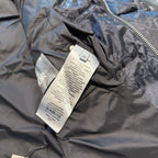 Dior size and care tags on interior lining of dark logo puffer jacket, close-up.