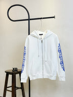 White zip-up hoodie with blue graphic sleeves, drawstring hood, and front pockets