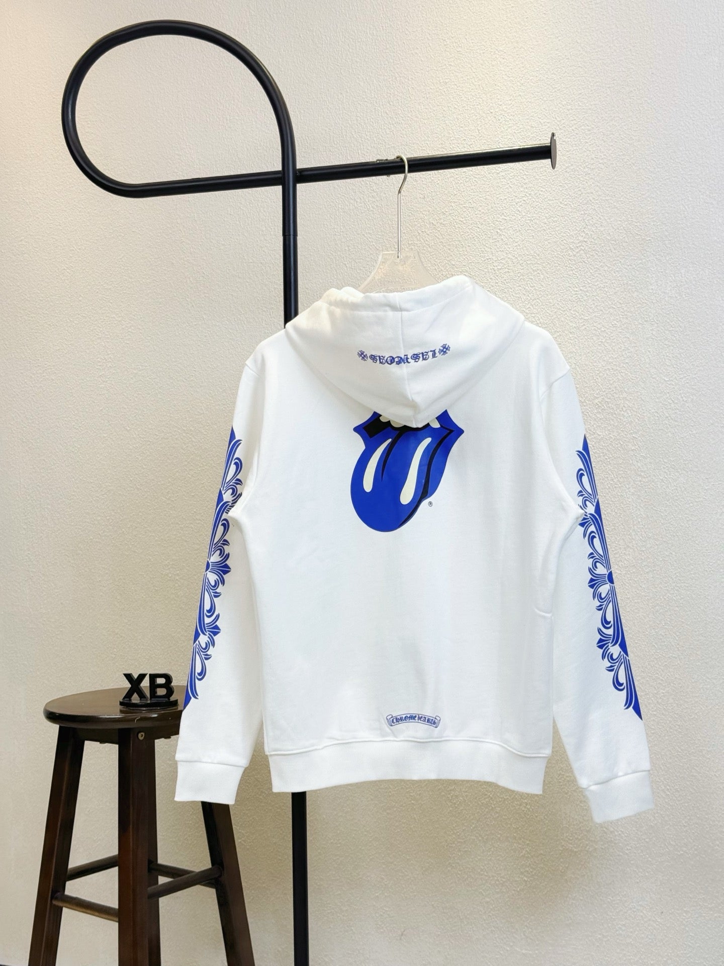 White hoodie front view with blue flame-like emblem and hood drawstrings