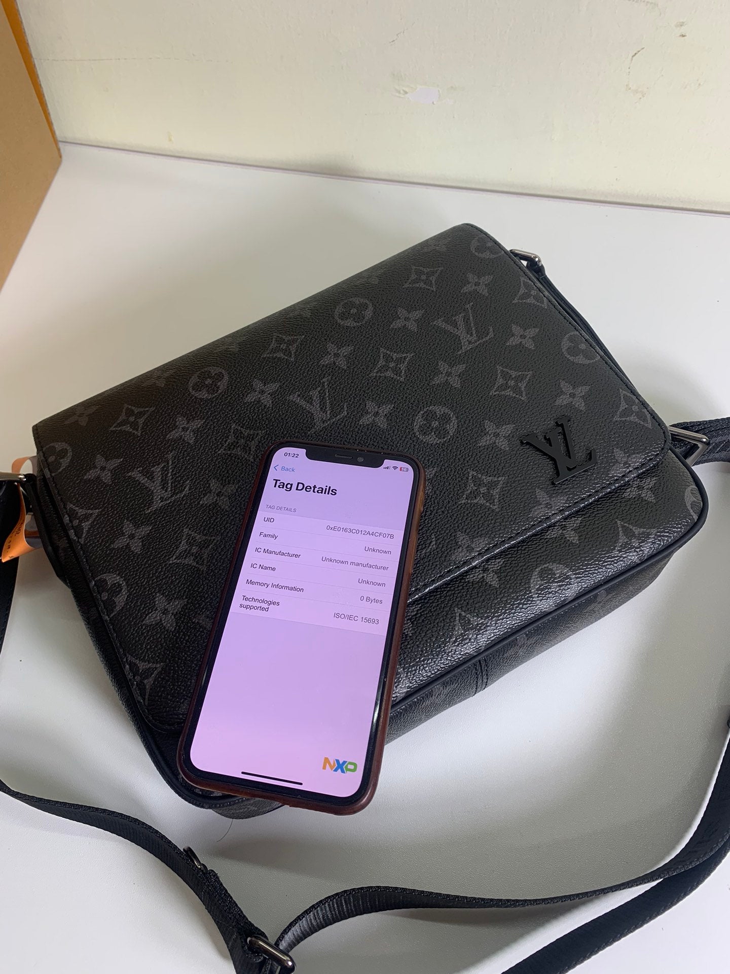 Louis Vuitton monogram crossbody bag with phone showing in front pocket, dark gray.
