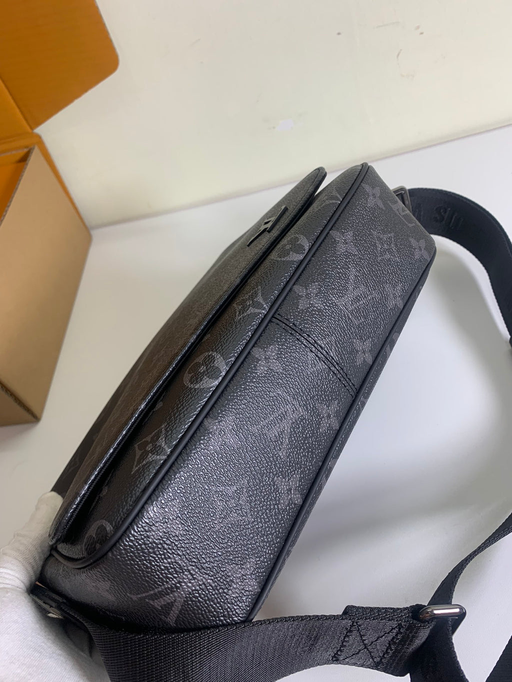 Louis Vuitton monogram crossbody bag on strap, dark gray with textured finish.