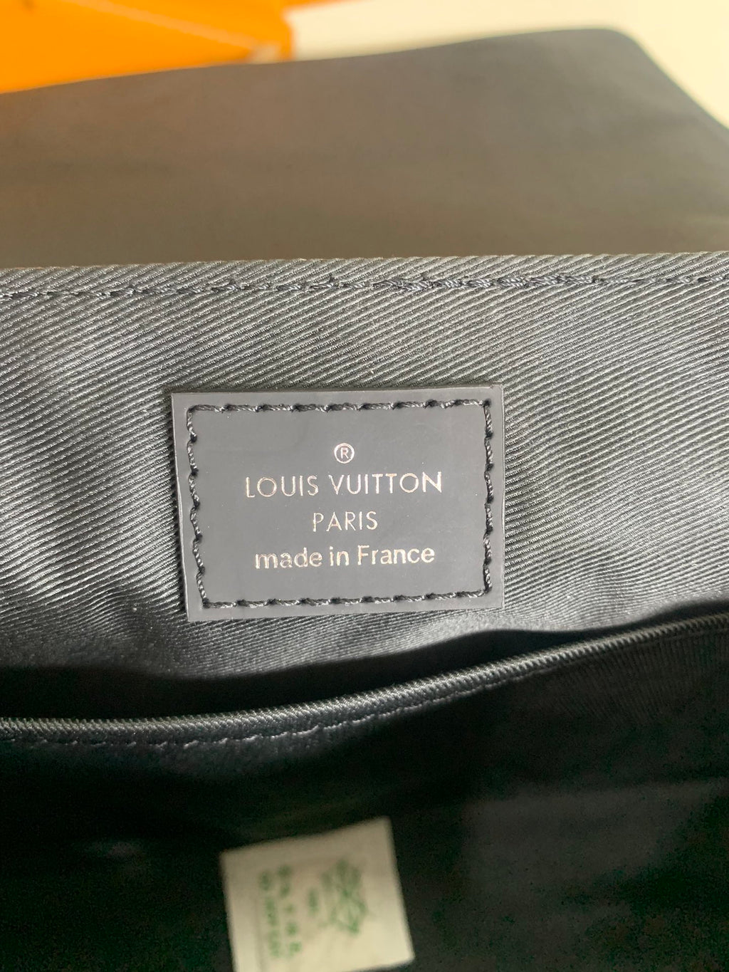 Louis Vuitton leather bag label patch, made in France on dark fabric