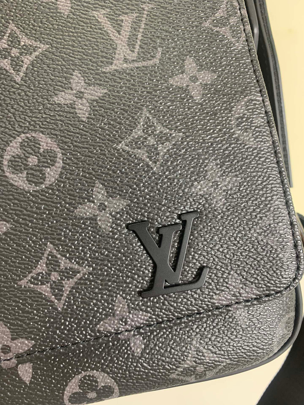 Louis Vuitton monogram crossbody bag close-up of LV logo on dark gray leather.