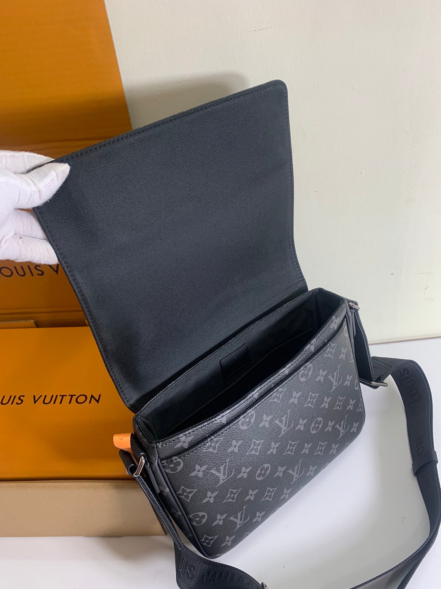 Louis Vuitton crossbody bag with flap opened, dark gray exterior and black lining.