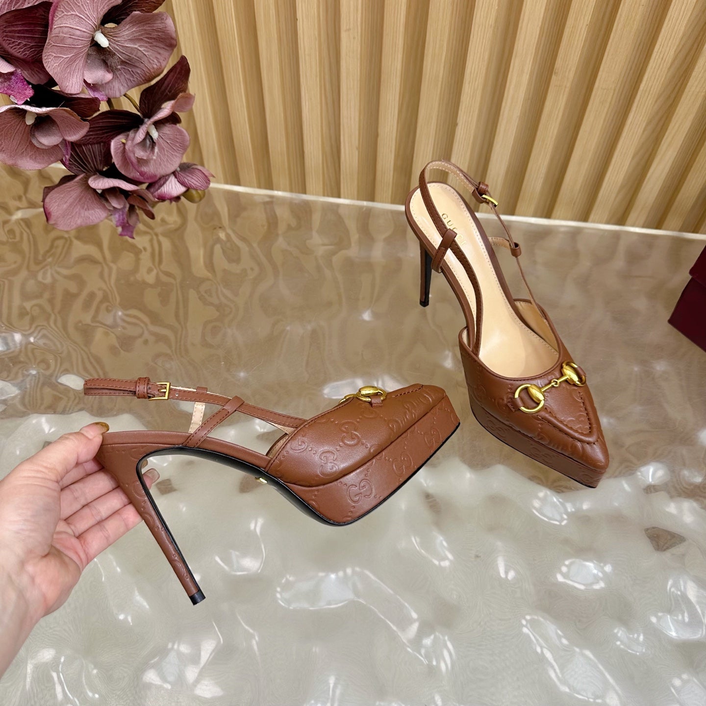 Brown Gucci slingback heeled mule with thin stiletto heel and gold ring buckle
