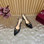 Black slingback stiletto heels with gold hardware, angled side view