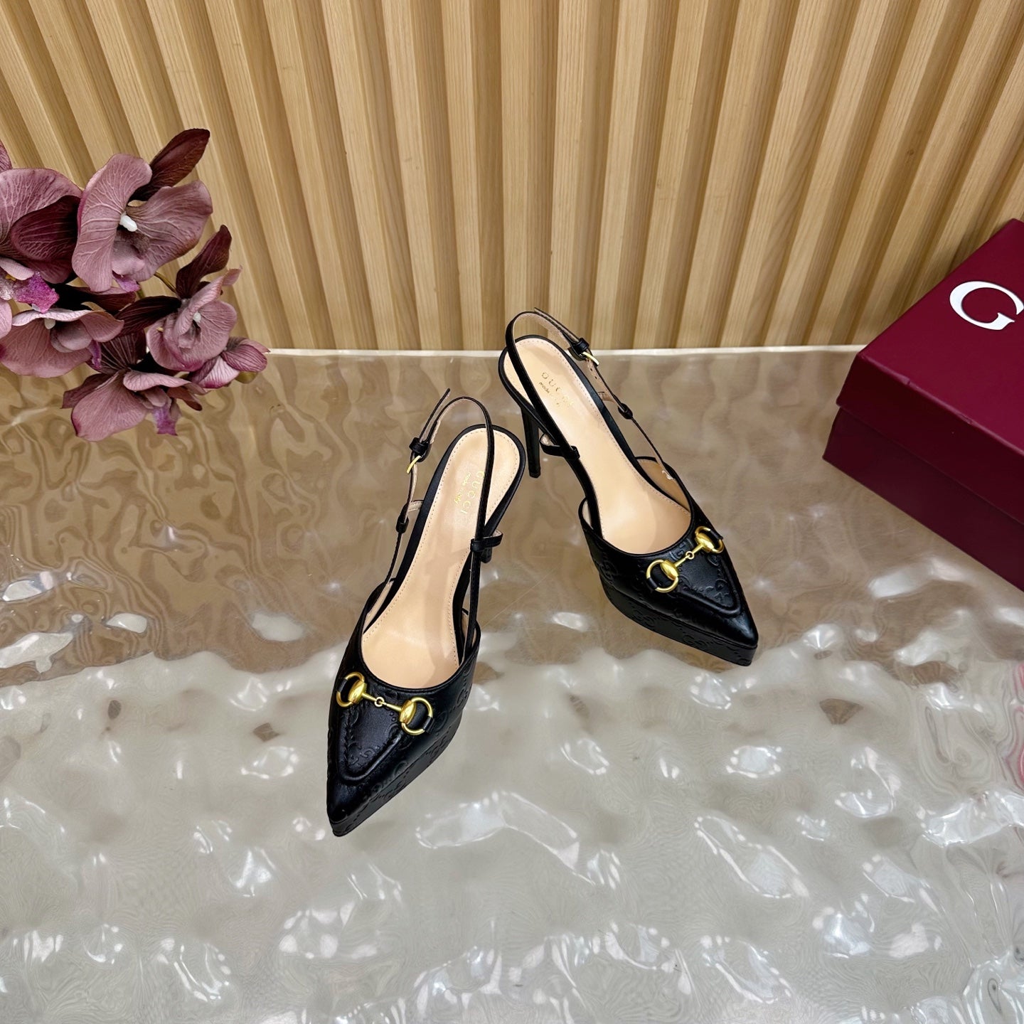 Black slingback stiletto heels with gold hardware, angled side view