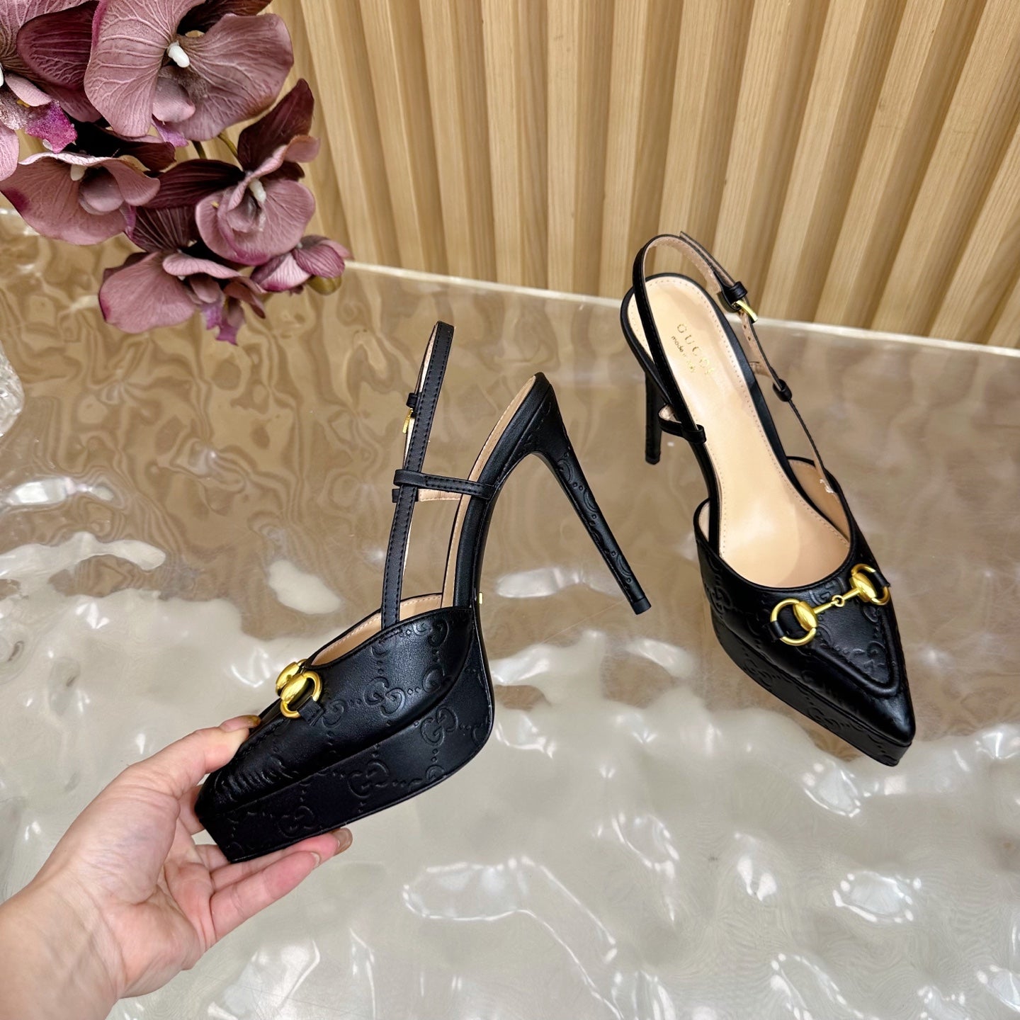 Black slingback stiletto heels with gold buckle detail, showing heel and strap