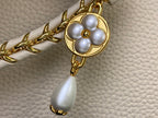 Louis Vuitton bag charm with gold flower and pearl drop on white textured leather