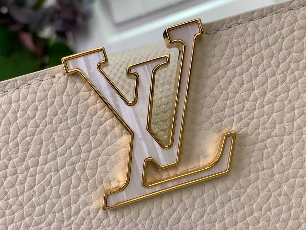 Louis Vuitton gold monogram emblem on white textured leather bag