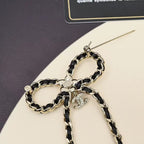 Chain charm necklace close-up with interlocking rings, floral medallion, and dangling charms