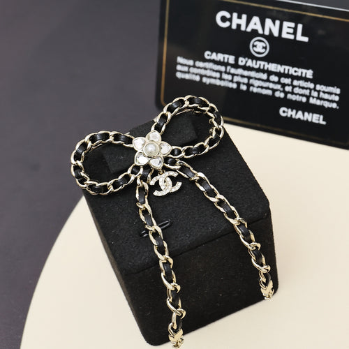 Chain charm necklace with interlocking metal links, floral pendant, and dangling strands
