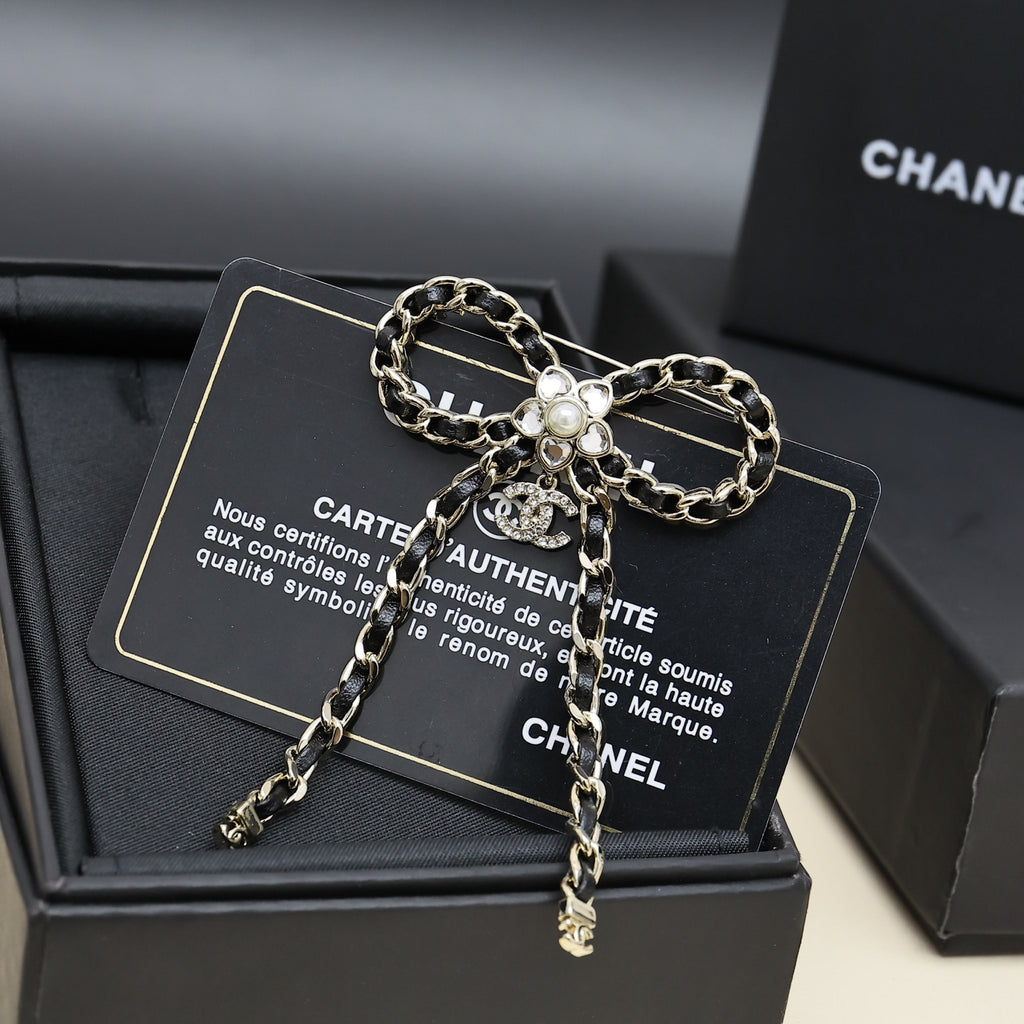 Chain charm necklace with floral pendant and dangling chain drops on a black display card
