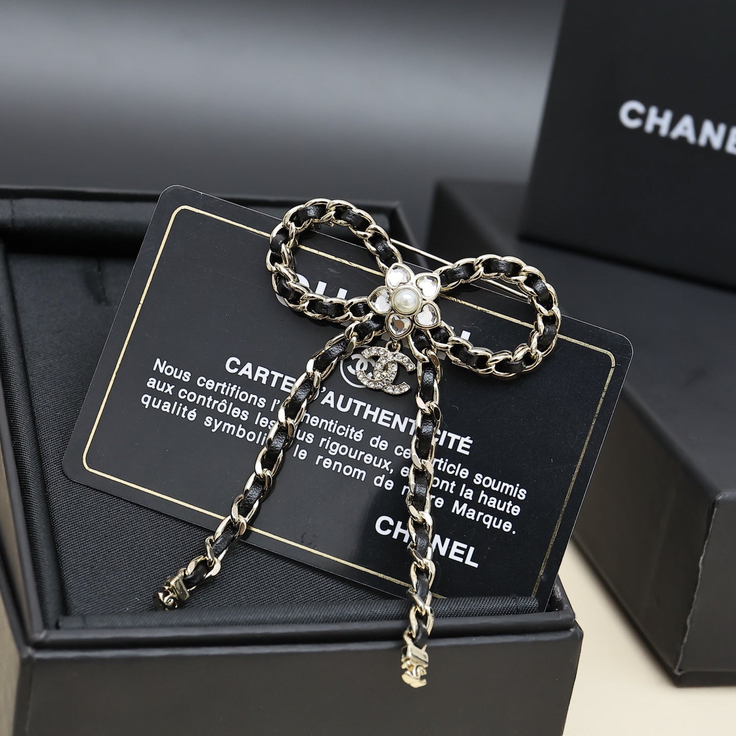 Chain charm necklace with floral pendant and dangling chain drops on a black display card