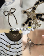Chain charm necklace with floral centerpiece and dangling charms on a person wearing a striped top
