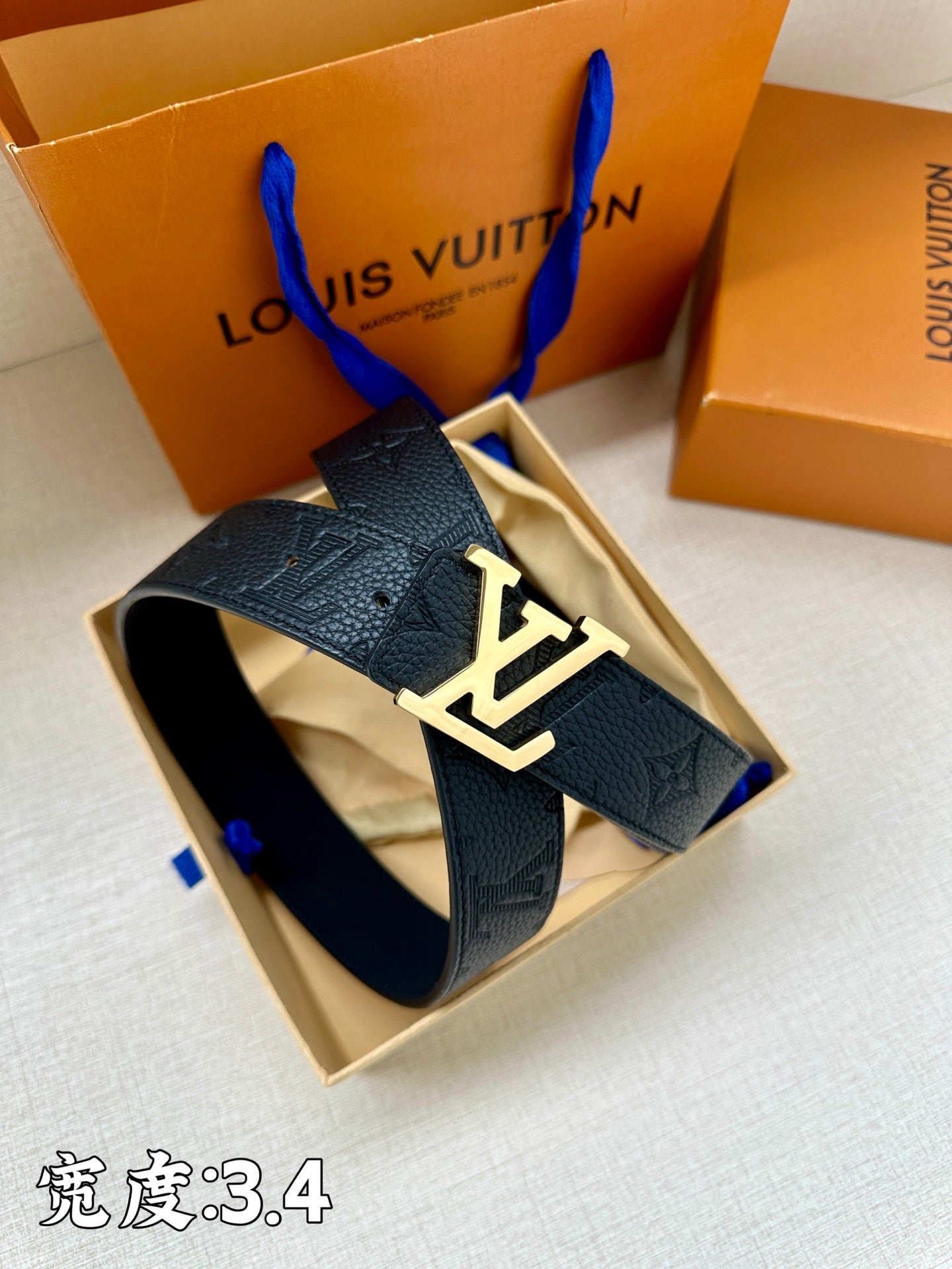 Dark blue leather belt with gold-tone LV buckle, shown in the gift box