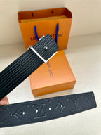 Hand holding dark blue Louis Vuitton belt with silver buckle and embossed pattern