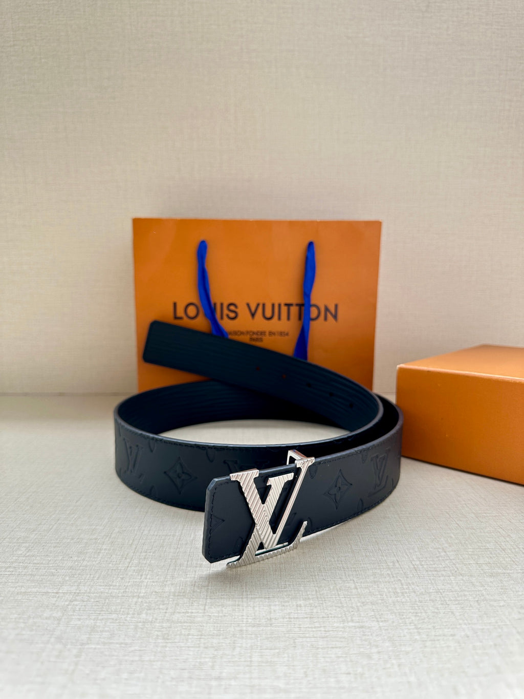 Dark blue Louis Vuitton belt with silver-toned buckle on display