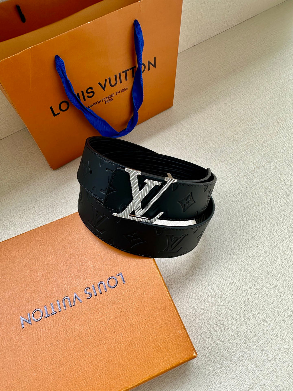 Dark blue leather belt with gold-toned LV buckle and embossed monogram