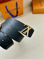 Dark blue leather belt with embossed monogram and gold buckle close-up