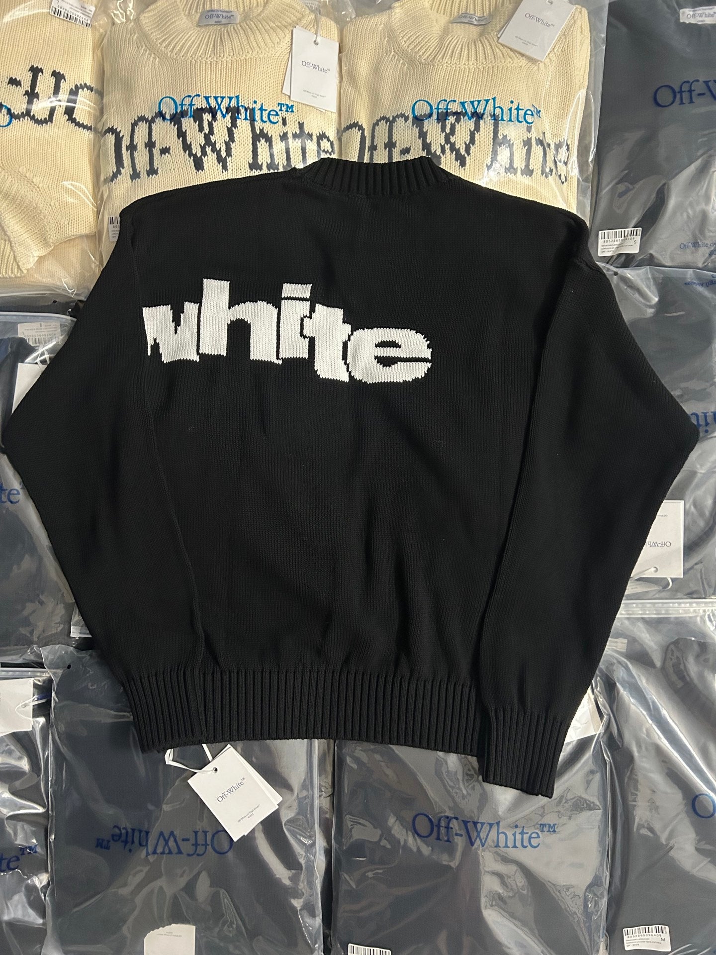 Black knit sweater back with white 'white' text logo
