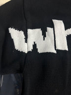 Black knit sweater close-up of white 'wit' text logo