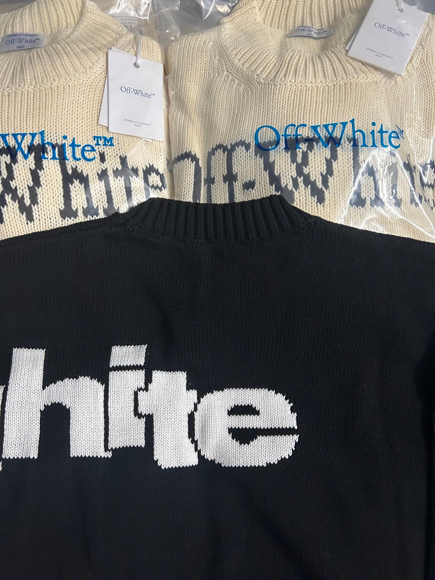 Black knit sweater close-up with white 'the' Off-White text on chest