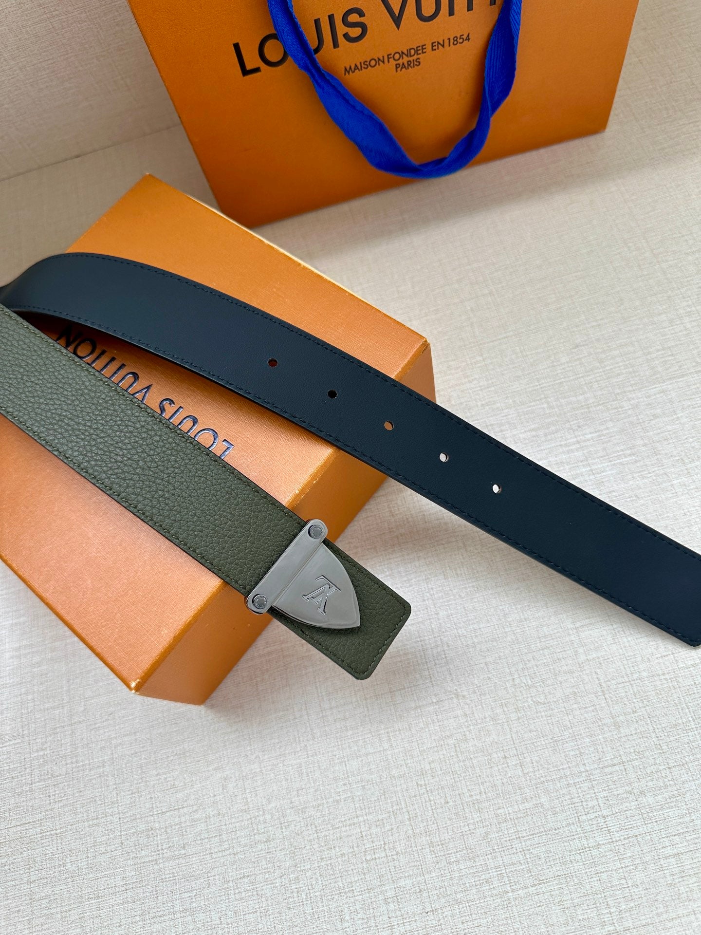 Two-tone green belt strap with metal buckle, laid flat
