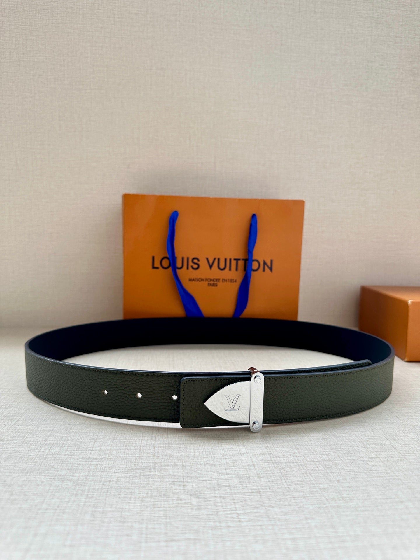 Green leather belt with silver rectangular buckle and engraved emblem