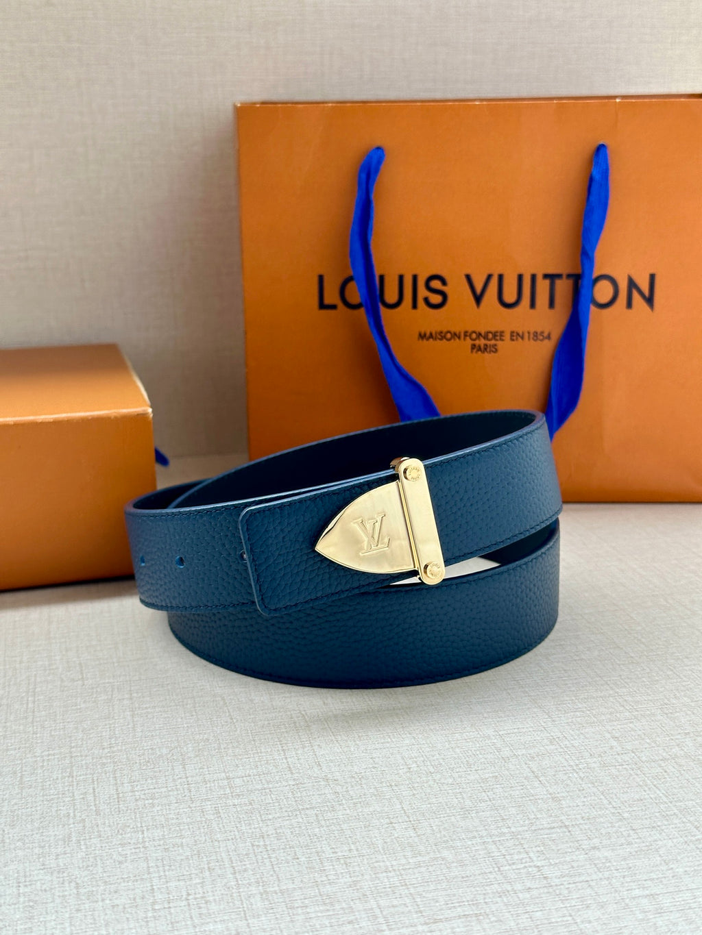 Blue leather belt with silver buckle and LV monogram plate, circular loop view