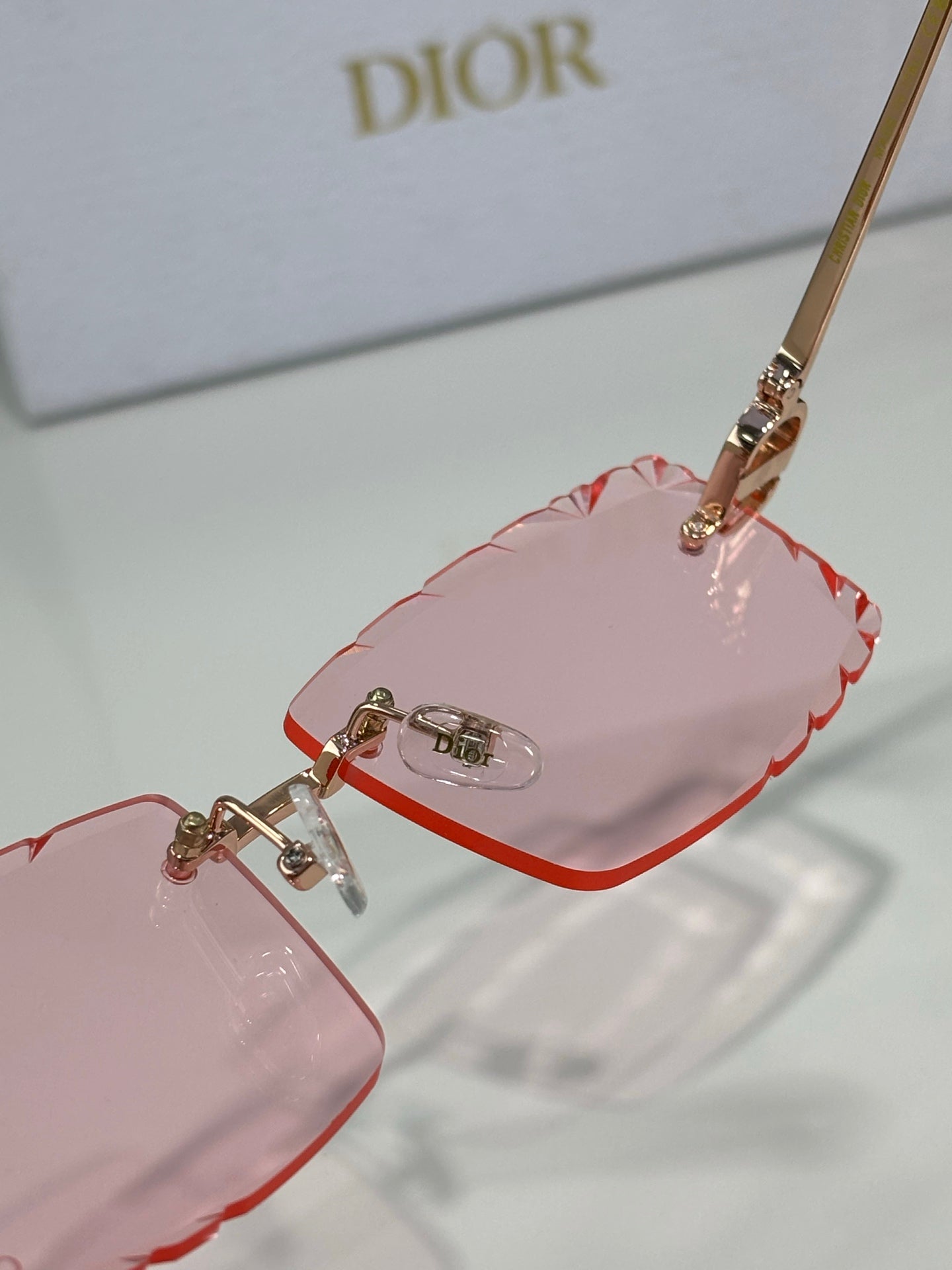 Dior sunglasses close-up with pink lenses and gold-tone temple hardware