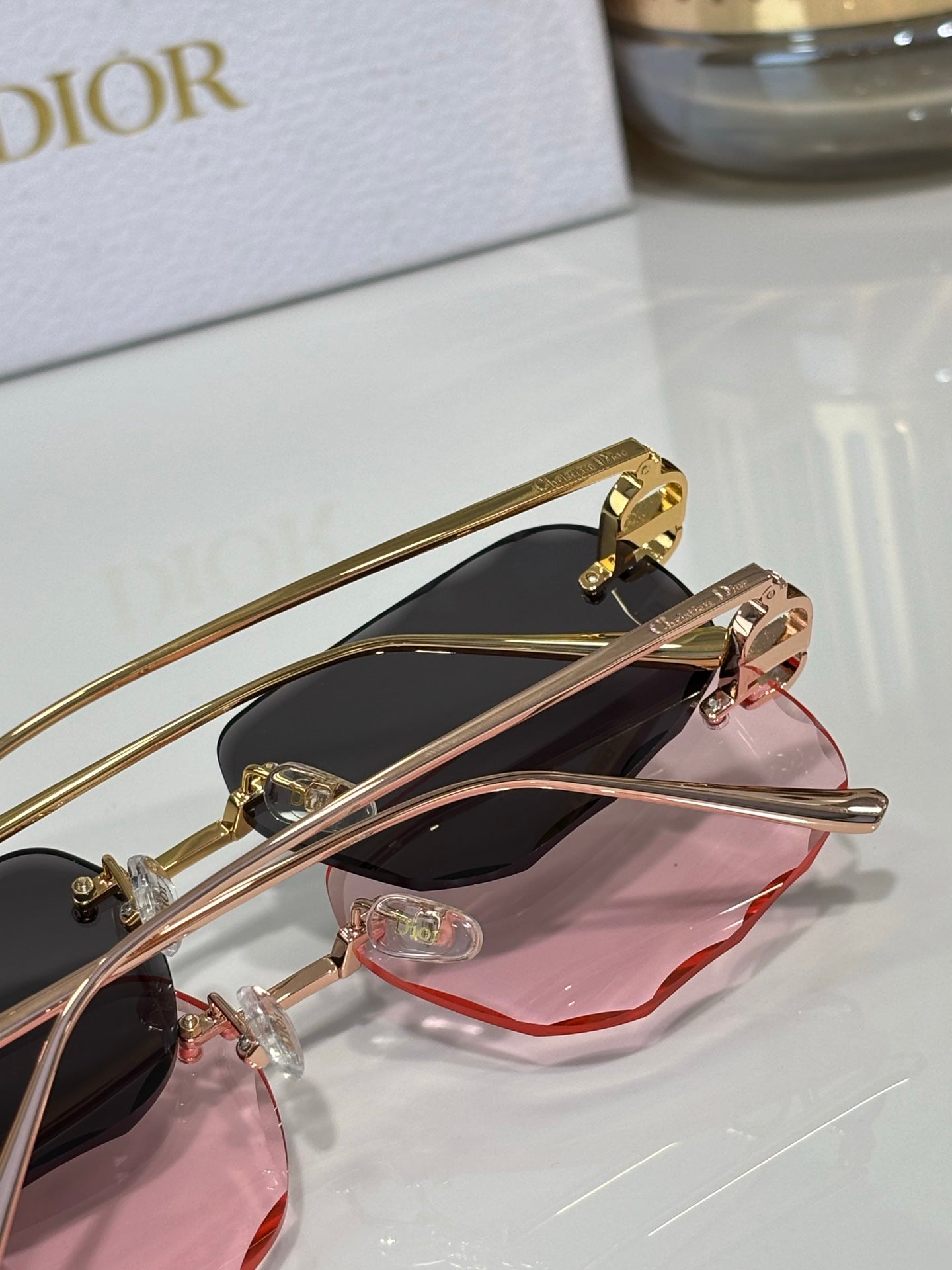 Sunglasses close-up with dark lenses and pink lens cover, gold-tone frame
