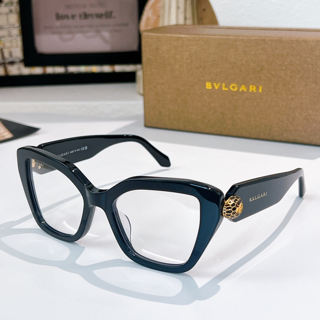 Dark blue sunglasses with clear lenses and a gold medallion detail on the temples