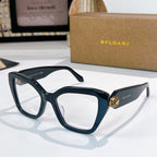 Dark blue sunglasses with clear lenses and a gold medallion detail on the temples