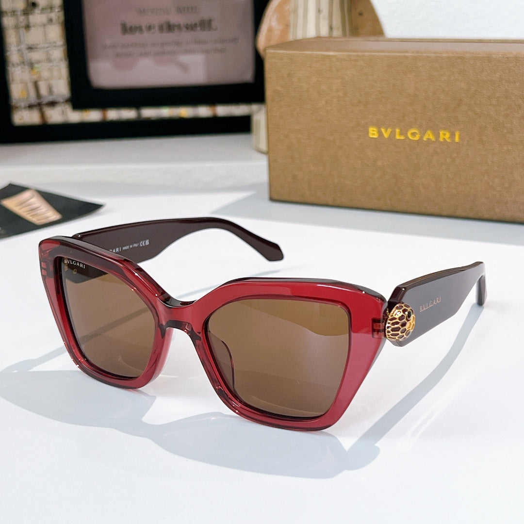 Red sunglasses with brown lenses and gold medallion detail on the temples