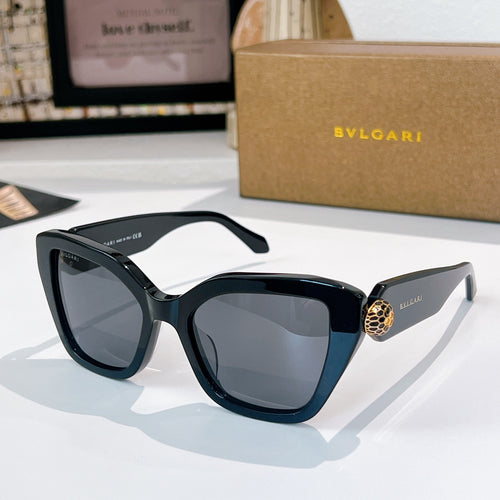 Black sunglasses with gray-tinted lenses and a gold medallion detail on the temples