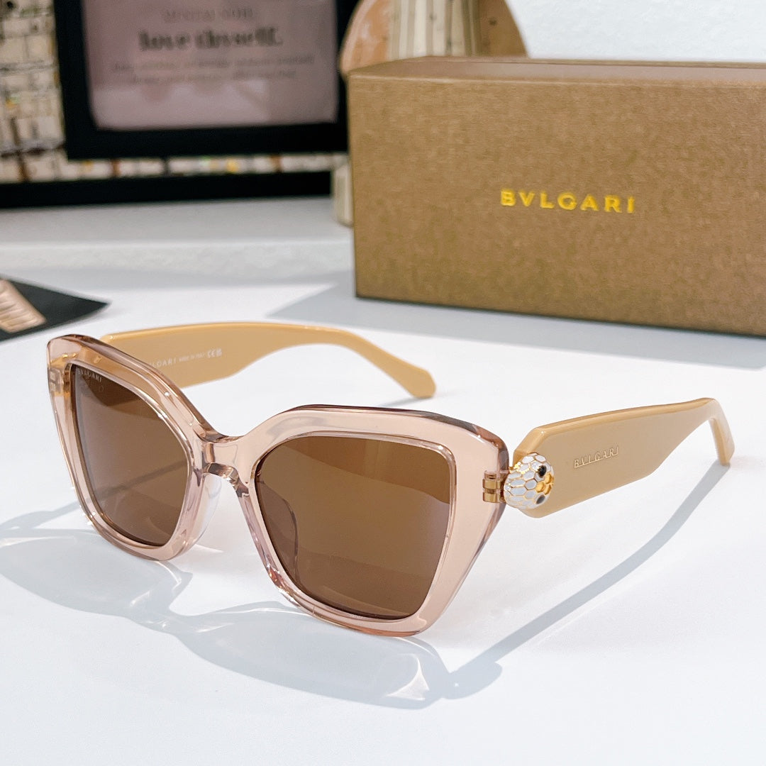 Light pink sunglasses with brown lenses and a gold medallion detail on the temples