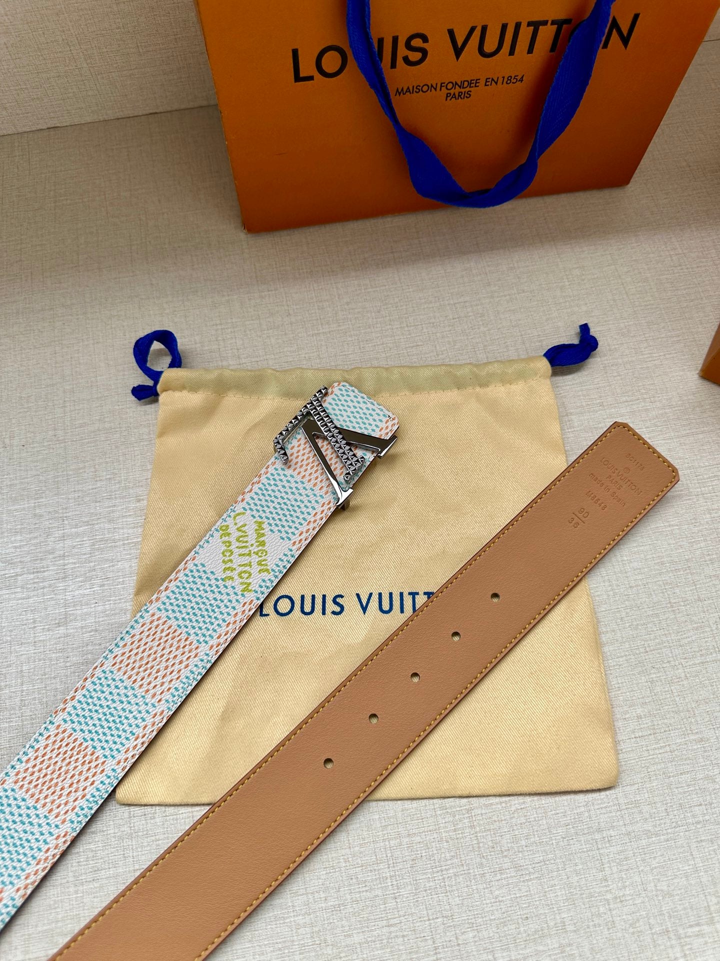 Canvas belt with silver buckle, tan leather strap, and matching dust bag