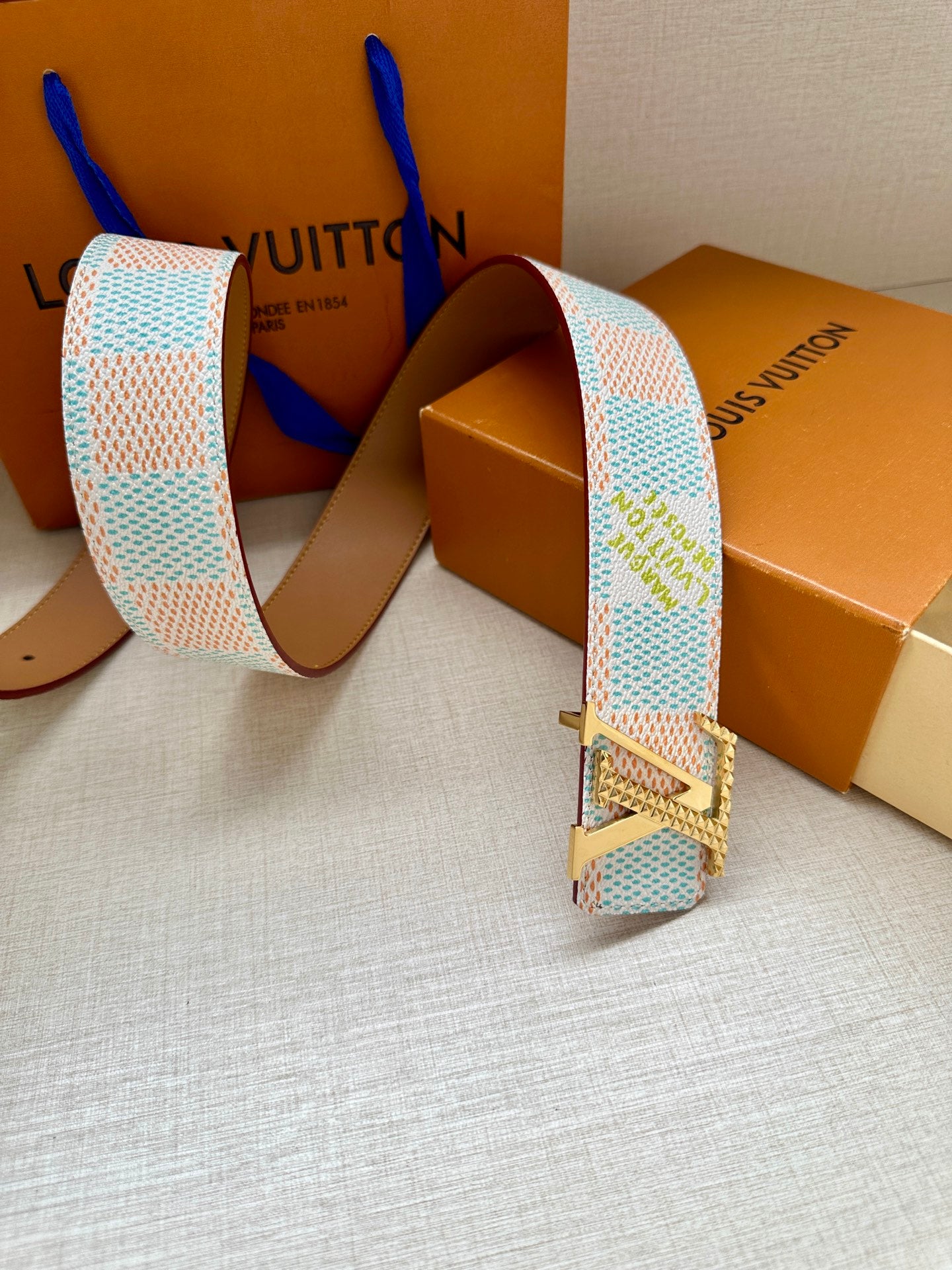 Designer belt with patterned canvas strap and silver buckle with leather keeper