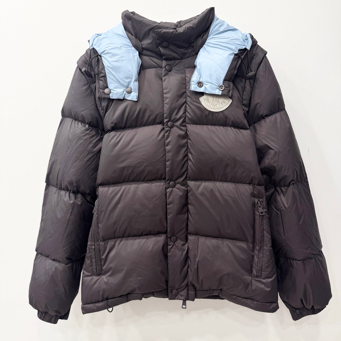 Long dark puffer jacket with hood, quilted panels, snap buttons, elastic cuffs