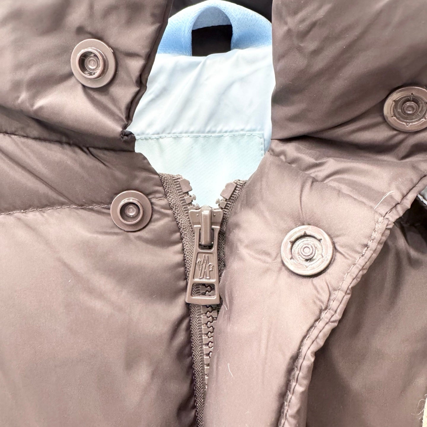 Puffer jacket zipper placket with metal snap buttons and contrasting inner lining