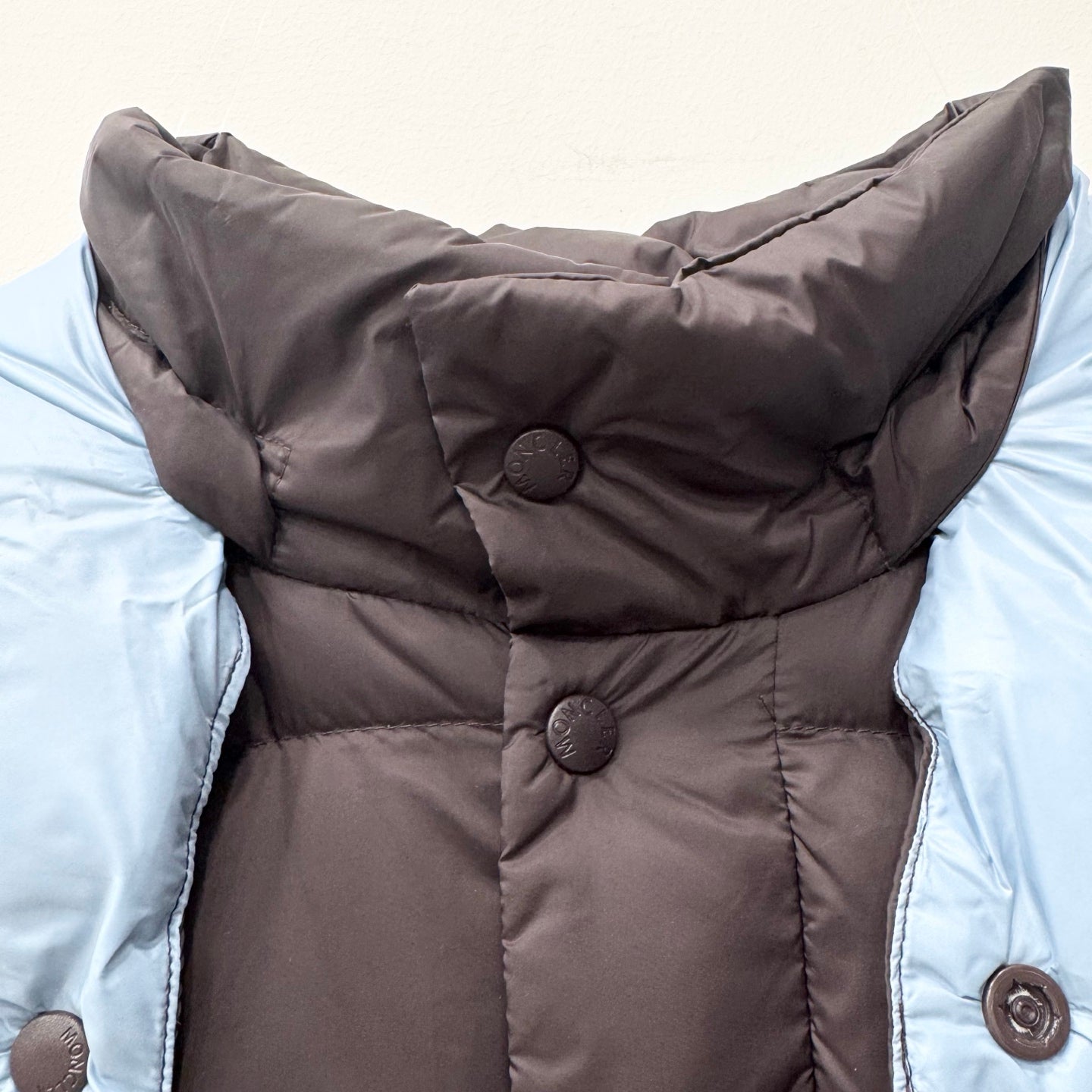 Long puffer jacket front with snap buttons and hood lining, quilted dark fabric
