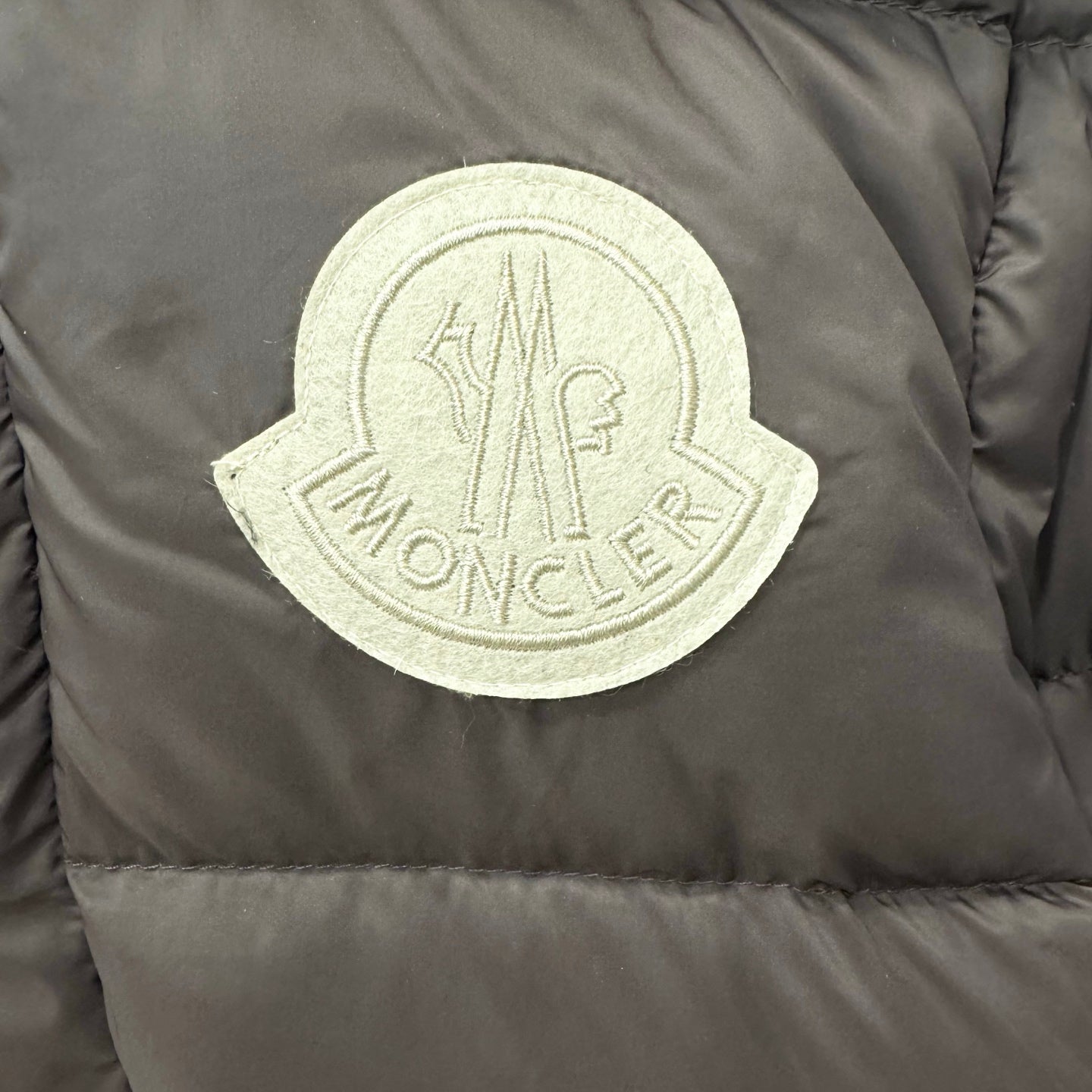 Embroidered logo patch on dark puffer jacket fabric