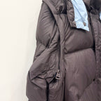 Long dark puffer jacket with hood, full zipper, and quilted body panels