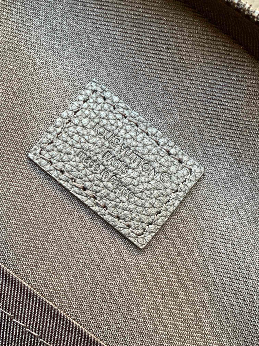 Louis Vuitton dark leather inner label with embossed text on textured fabric