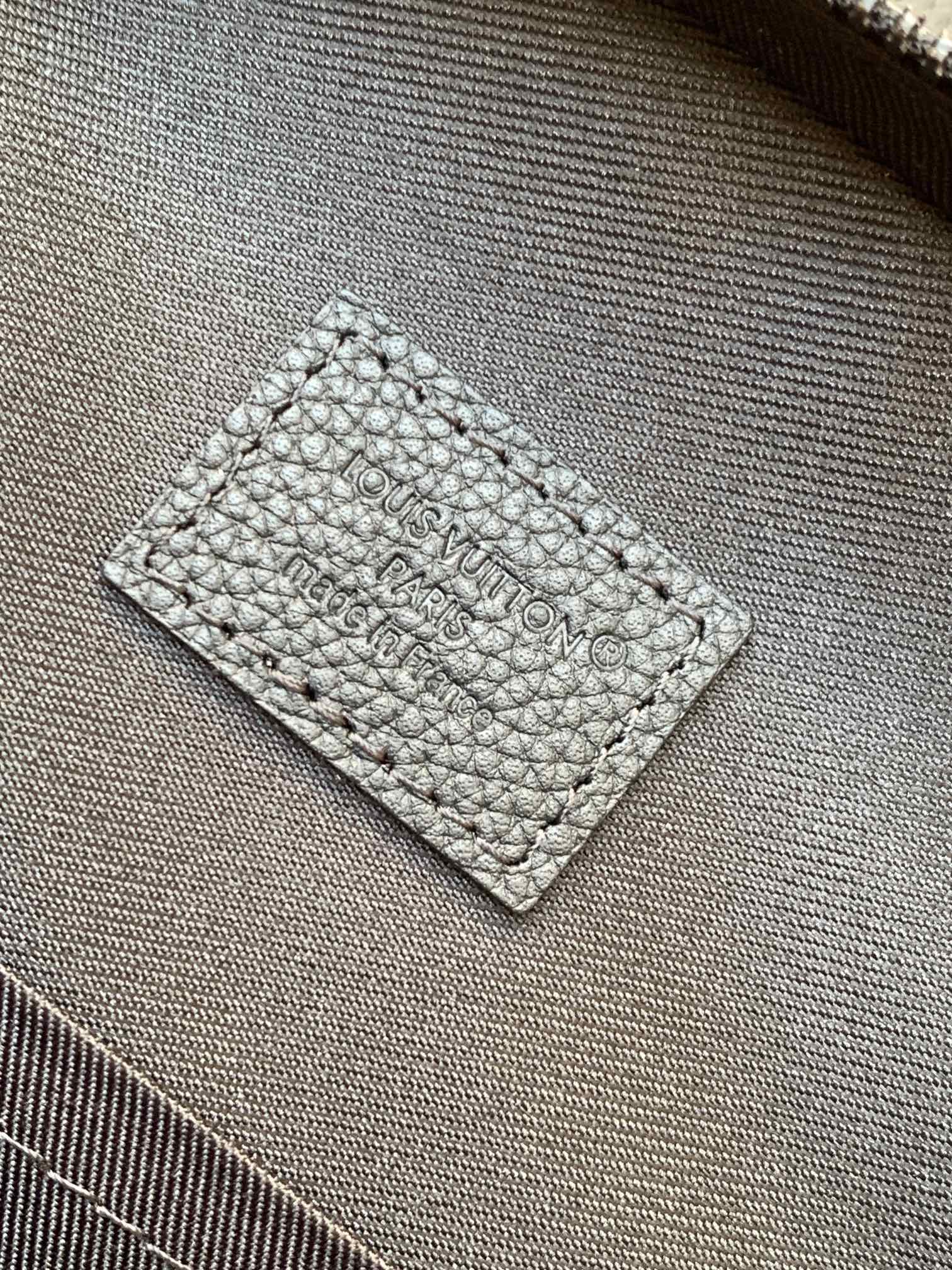 Louis Vuitton dark leather inner label with embossed text on textured fabric
