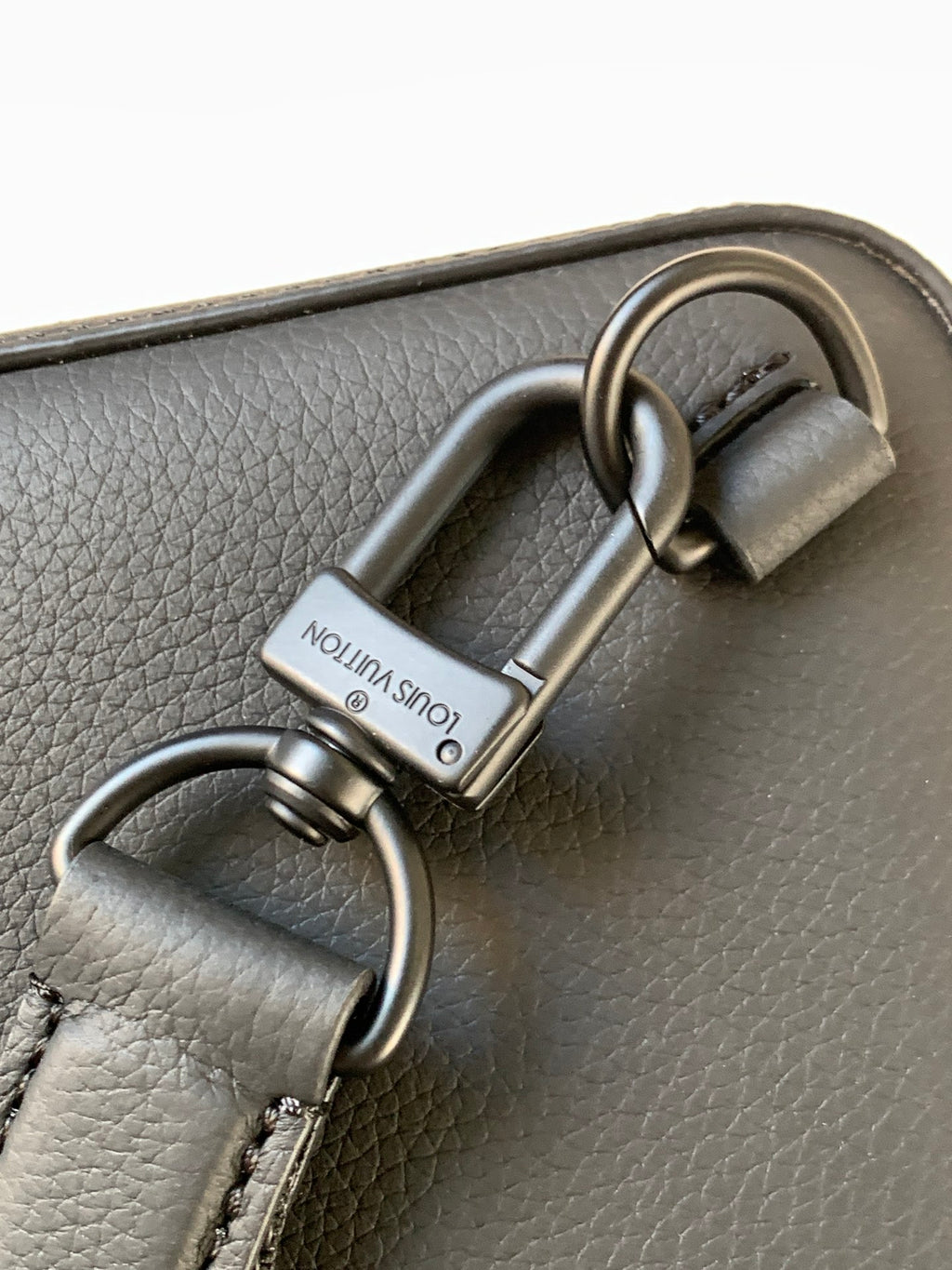 Louis Vuitton dark leather bag strap hardware with engraved metal buckle and rings