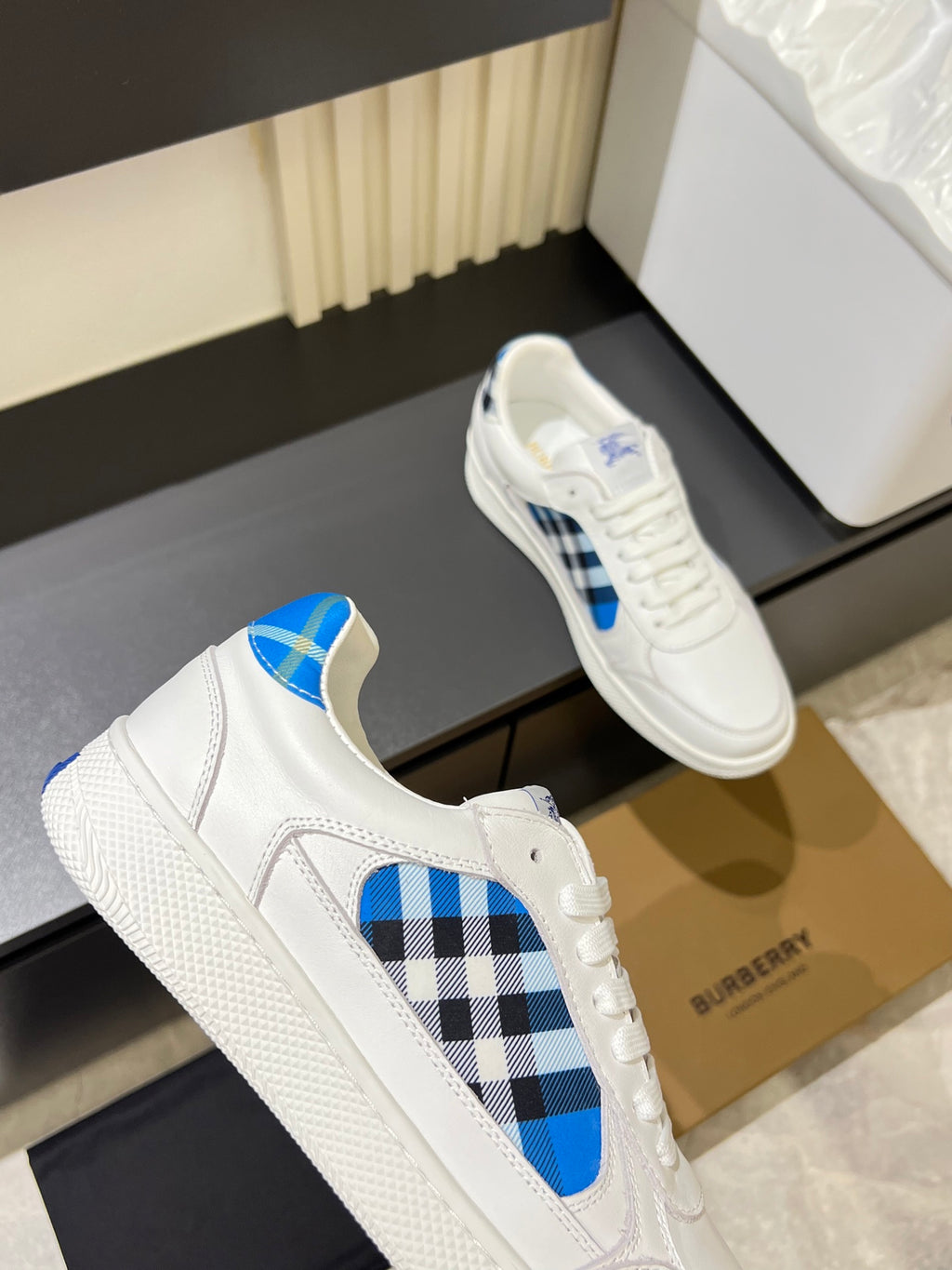 White Burberry sneakers close-up side view with blue and black check motif